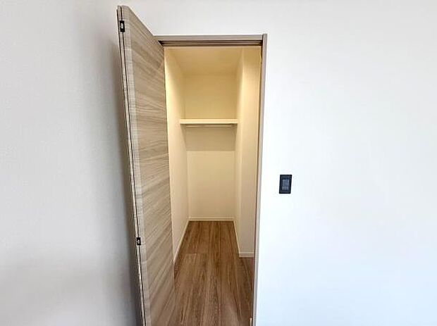 扉付きの収納スペースは整理整頓に便利です。奥行きがあり収納力があります。床はフローリングで清潔感があります。上部には棚も設置されています。