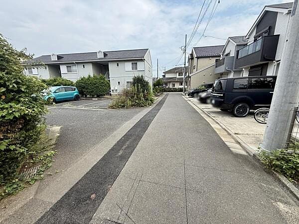 周囲には落ち着いた雰囲気の住宅が並んでいます。道路は舗装されており整然とした印象があります。駐車スペースも複数確保されています。道路幅も十分で車の出し入れも安心です。植栽も見られ緑が感じられます。
