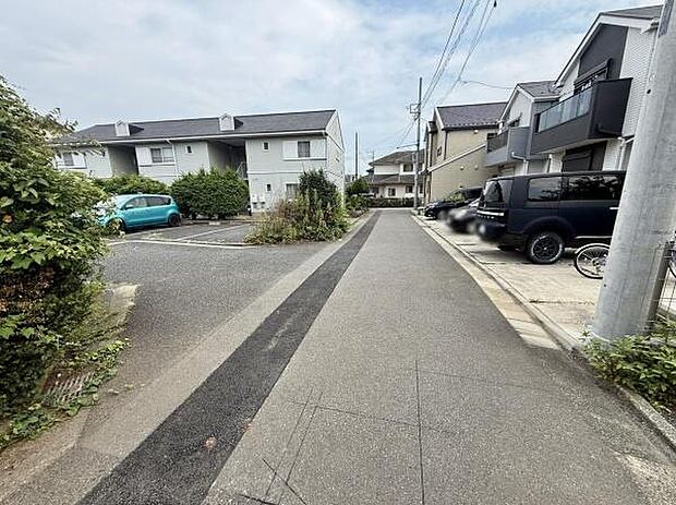周囲には落ち着いた雰囲気の住宅が並んでいます。道路は舗装されており整然とした印象があります。駐車スペースも複数確保されています。道路幅も十分で車の出し入れも安心です。植栽も見られ緑が感じられます。