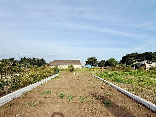 青空が広がる開放的な現地土地写真です。周囲は緑に囲まれており見晴らしが良いのが特徴です。整備された区画がしっかりと確保されているためさまざまな活用が可能です。