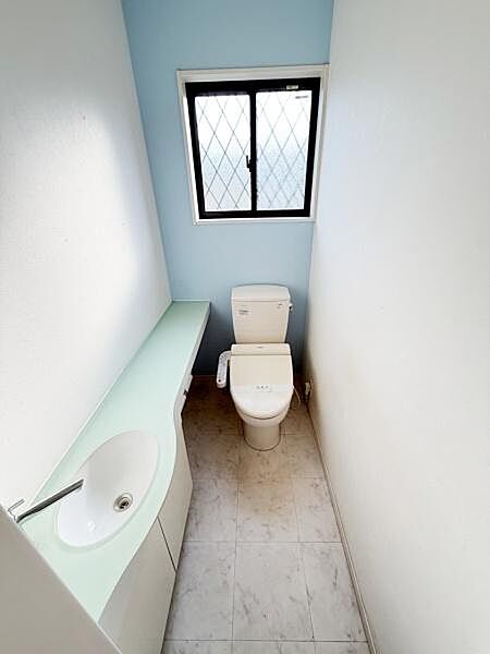 明るい窓付きのトイレは換気がしやすく清潔感があります。手洗いカウンターが備わっていて便利です。シンプルで落ち着いた内装が印象的です。ゆとりある空間設計になっています。