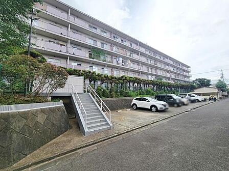 整備された外観が印象的なマンションです。敷地内には駐車スペースも配置されています。植栽がきれいに管理され落ち着いた雰囲気です。日当たりが良好な印象を受けます。
