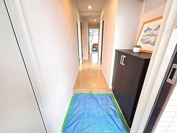 玄関は明るい照明によりすっきりとした印象を与えます。シューズボックスが設置されており収納面も配慮されています。床は清潔感があり内装全体が整った空間です。