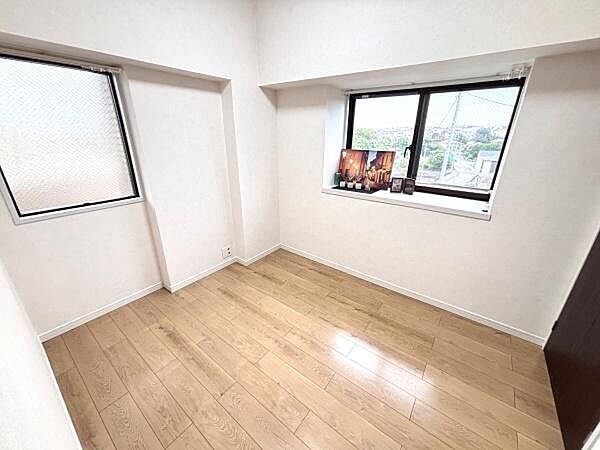 明るい窓からたっぷりと自然光が入る寝室です。すっきりとした内装で落ち着いた雰囲気が広がります。床はナチュラルな色合いで清潔感があります。二面に窓が配置されており風通しが良好です。