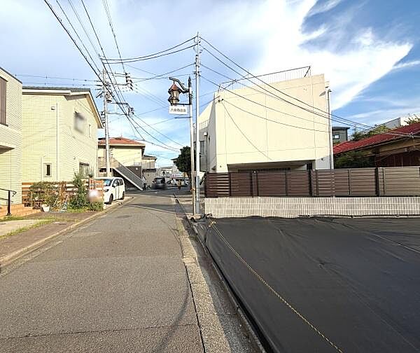 前面道路はすっきりと整備されており広めの通行スペースが確保されています。周囲には落ち着いた住宅が立ち並び見通しの良い環境です。道路は緩やかな傾斜で歩道も歩きやすいです。