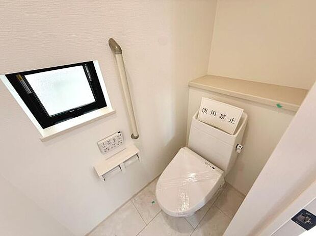 明るい窓があり自然光が差し込むトイレです。手すりが設置されていて使いやすさにも配慮されています。収納スペースも確保されておりシンプルで清潔感のある空間です。