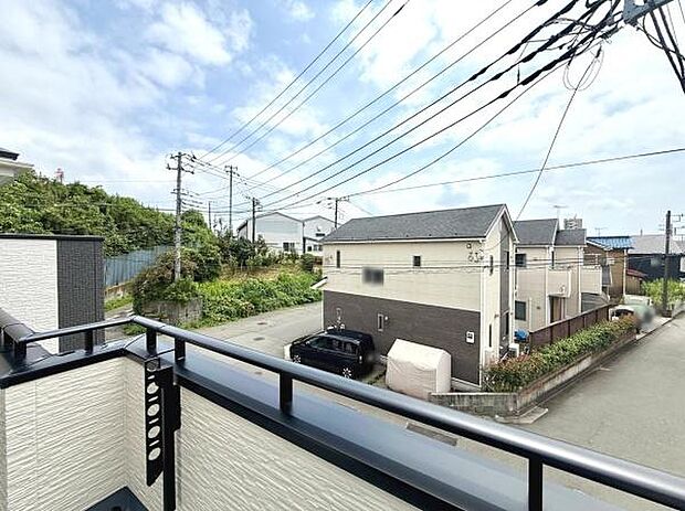 バルコニーから周辺の住宅街を一望できる現地からの眺望です。開放感のある景色が広がっています。前面道路が広く車の出し入れもしやすい印象です。周囲の住宅が整然としており落ち着いた雰囲気が感じられます。