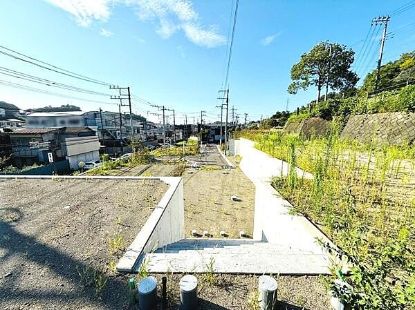 現地土地写真から広がる開放感のある景色が印象的です。陽当たりの良さを感じることができる場所です。インフラ設備が整った状態で周囲には緑も見られます。形状も整備されていて使い勝手が良さそうです。