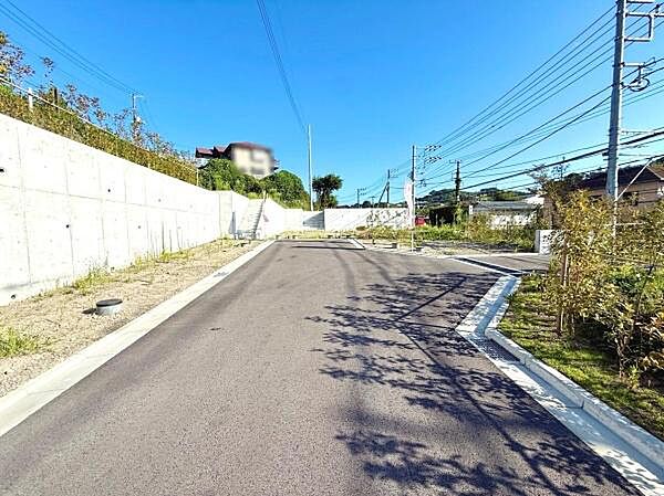 前面道路が広々としており車の出し入れがスムーズに行えます。周囲の住宅や植栽も整備されており明るい印象の現地写真です。舗装状態も良く安心してご利用いただけます。
