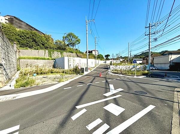 幅広い前面道路が特徴的で車両の通行も安心感があります。道幅がしっかり確保されているので見通しも良好です。周囲には緑も見られすっきりとした街並みが印象的です。電柱や標識もしっかり整備されています。