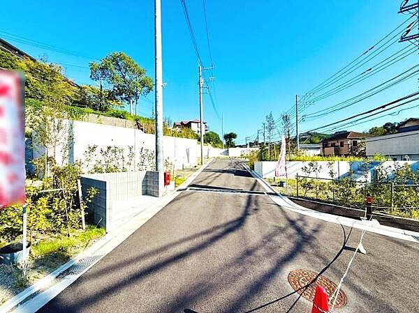 現地写真からも分かるように前面道路は幅が広く車の通行やすれ違いもスムーズです。道路沿いは緑が多く開放的な雰囲気が感じられます。周辺は整備された印象で落ち着いた住宅街の一角です。