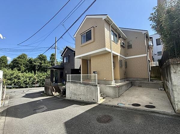 前面道路が広々としており車の出し入れがしやすいです。住宅の外観は落ち着いた色合いで周囲の街並みと調和しています。段差のあるエントランスがアクセントになっています。周辺には緑も見え環境を感じられます。