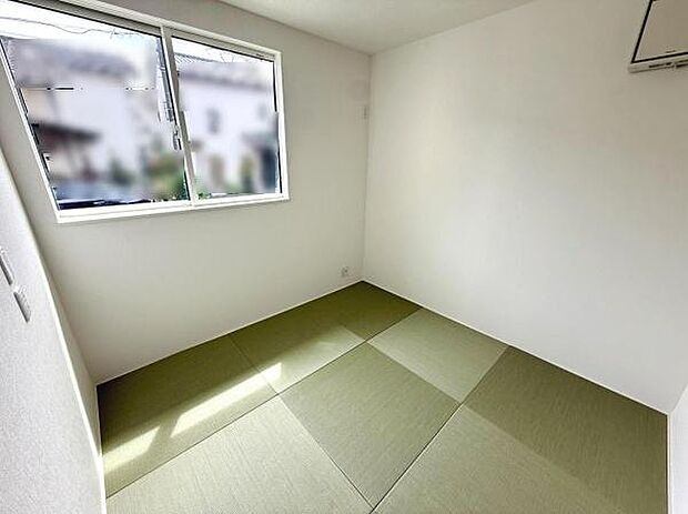 シンプルで落ち着いた雰囲気の和室です。大きな窓から光が差し込み明るい室内を演出しています。すっきりとした壁と畳が調和する空間です。柔らかな畳の色合いが印象的です。さまざまな用途に活用しやすい和室です。