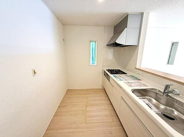 白を基調とした明るいキッチンです。窓があり通気性にも配慮されています。作業スペースが広く日々の調理も快適に進められます。収納も充実しておりキッチン周りがすっきり保てます。清潔感のある空間が印象的です。