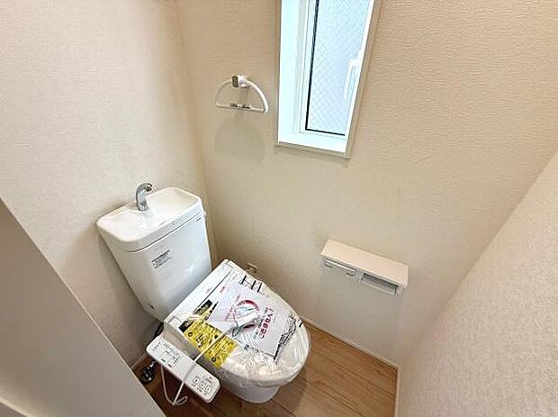 シンプルな内装のトイレです。小窓があり採光や換気に便利です。温水洗浄便座が設置されており使い勝手も意識されています。ペーパーホルダーやタオル掛けも付いています。