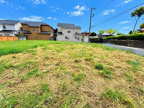 落ち着いた住宅街に位置する現地土地写真です。周辺には家々が建ち並び閑静な雰囲気が広がっています。きれいに整地された敷地はお好きなプランの実現に適しています。