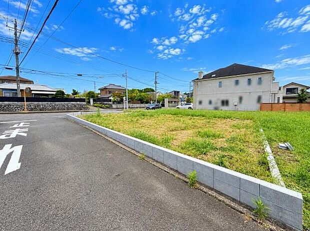 現地写真からは整備された前面道路と広々とした敷地の様子がうかがえます。周辺は住宅が建ち並び落ち着いた住環境が感じられます。敷地内は陽当たりも確保されています。