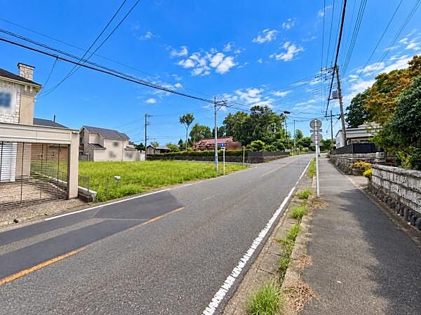 前面道路は幅が広く車の通行もスムーズに感じられます。周囲には住宅や緑もあり開放感があります。現地写真から周辺の雰囲気や空の広がりも確認できます。道路沿いの歩道も整備されており利用しやすい印象です。