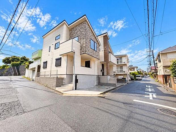 角地に位置する現地写真で道路幅にも余裕が感じられます。陽当たりの良さが建物の外観にも表れています。周囲には落ち着いた住宅が並び整然とした街並みです。建物の外観もモダンでシンプルなデザインが特徴です。