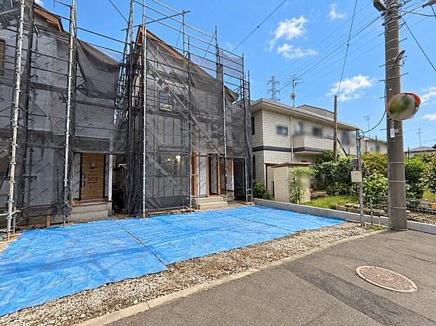 前面道路から建物までのアプローチが確保されています。建物は現在工事中で新生活に向けた準備が進んでいます。周辺には電柱やミラーも設置されており道路状況の確認に適しています。