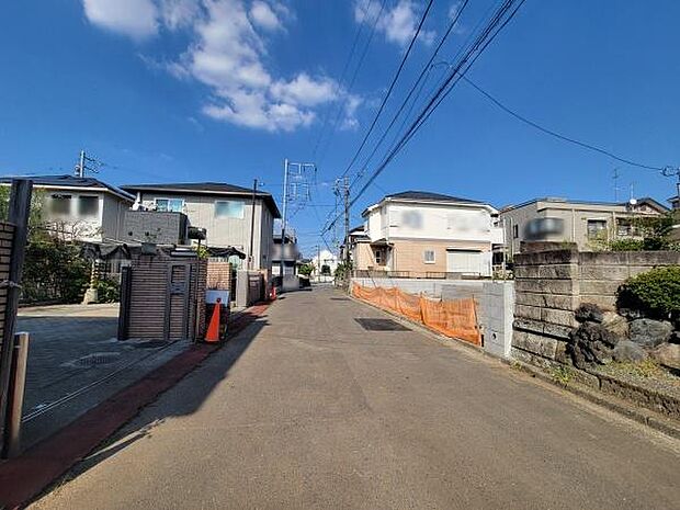 現地の前面道路はフラットで歩きやすい印象です。周囲は住宅が立ち並ぶ環境で道幅にも余裕があります。