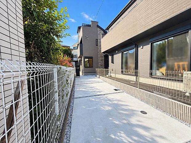 わが家へと続く専用アプローチが、日常に特別感をプラス。 道路から奥まった配置がプライベート感を演出。緑を感じながら歩くアプローチの先には、洗練されたグレーの新築邸宅。帰るたびに心が弾む住まいです。