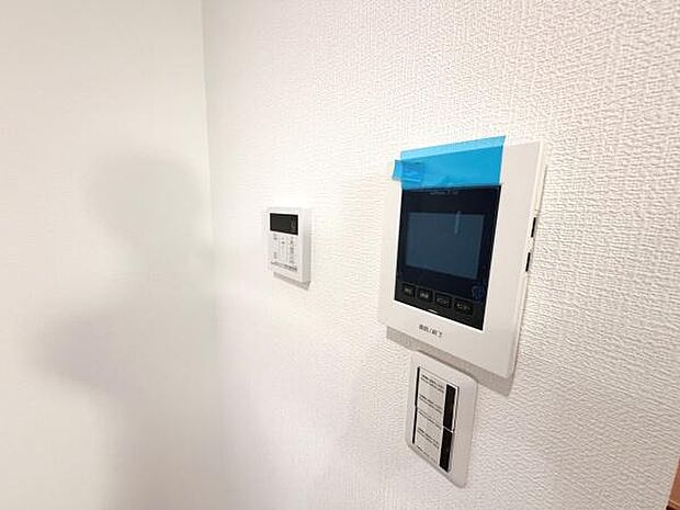 壁面に設置されたモニターやスイッチが整然と配置されています。シンプルなデザインで空間に調和しています。操作パネルが使いやすい高さに設置されています。壁の質感も落ち着いています。