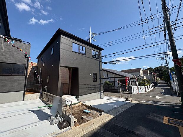 右が当物件。濃い色の外観が上品な印象を与える佇まい。(令和8年8月撮影)