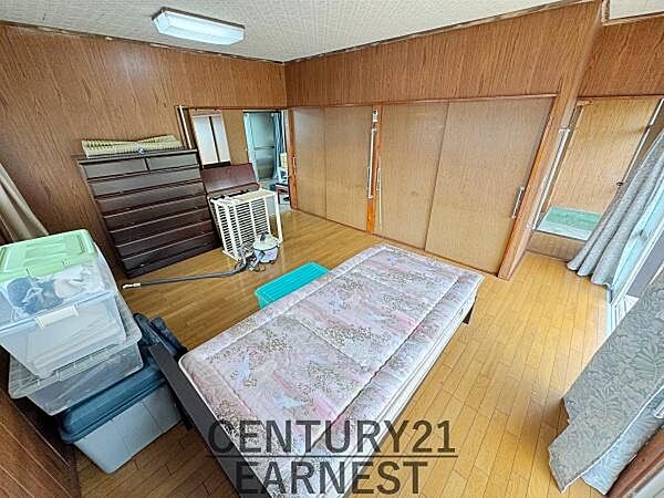木目調の壁が温かみを感じさせる寝室です。収納スペースも豊富にあり整理整頓がしやすくなっています。大きな窓からは自然光がたっぷり入り明るい雰囲気が広がっています。