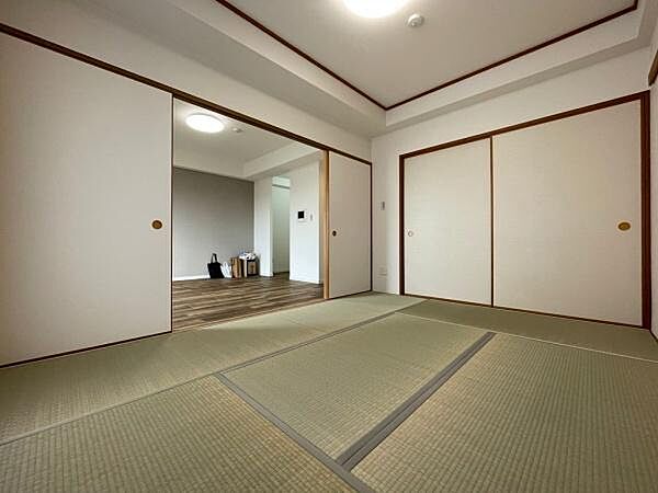 落ち着いた雰囲気の和室です。畳が清潔感を感じさせ収納スペースもあります。隣接する空間とゆるやかにつながっています。室内は明るく快適に過ごせそうです。照明の配置にも配慮されています。
