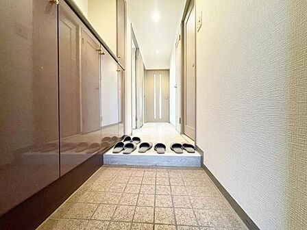 玄関スペースが広く収納も充実しています。シンプルで落ち着いた内装が特徴です。靴の収納にも便利な造りです。明るい照明で清潔感のある印象を与えます。廊下まで一直線に続く動線が使いやすいです。