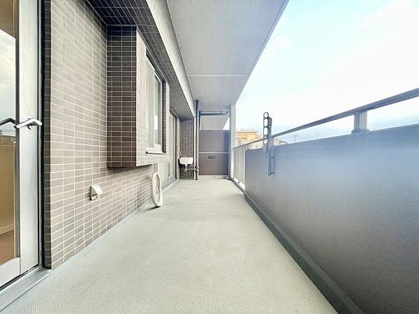 ゆとりのある広々としたバルコニーが特徴です。奥行きがあるため多様な用途にも活用できます。採光も良好で開放感があります。建物側のタイル貼りが印象的です。屋根付きで天候の影響も受けにくい設計です。