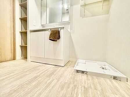 明るく開放感のある洗面所です。収納スペースが豊富な洗面台が設置されています。洗濯機置き場も確保されており機能的な空間となっています。清潔感のあるフローリングが特徴です。鏡面の仕様も便利です。