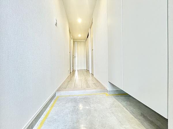 明るい照明が印象的な玄関です。廊下まで見通しが良く全体的にすっきりとしたデザインとなっています。足元のスペースにもゆとりが感じられます。白を基調とした内装が清潔感を演出しています。