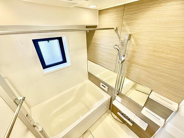 ナチュラルな色合いの壁面が空間を明るく演出しています。浴槽と洗い場がゆとりを感じさせます。換気窓が設けられておりバスルーム内の快適性に配慮されています。清潔感あふれるデザインが印象的です。