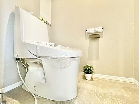 白を基調とした清潔感のあるトイレです。手入れのしやすい床材が採用されています。スペースにゆとりがあるため使いやすい印象です。壁にリモコンが設置されておりスッキリとしたデザインです。