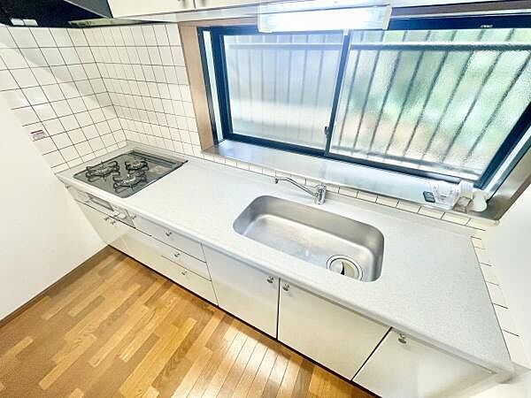 キッチンには広々とした作業スペースがあり使い勝手の良さが感じられます。窓が大きく自然光がたっぷり入るため明るい印象です。タイル壁による清潔感もポイント。
