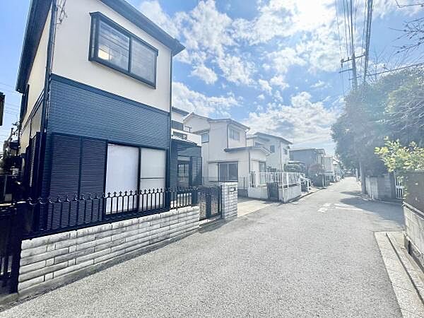 現地写真からは前面道路が広めで見通しの良い環境であることがうかがえます。道路は舗装されており車の通行も快適です。周辺には住宅が並び整然とした街並みが特徴的です。