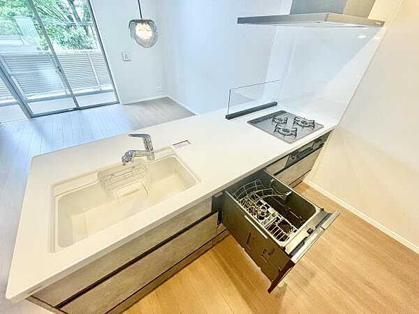 明るい空間に調和したキッチンです。食器洗浄機や三口コンロなど使いやすさを考えた設備が揃っています。広々としたワークトップで作業がはかどります。掃除がしやすい設計になっています。