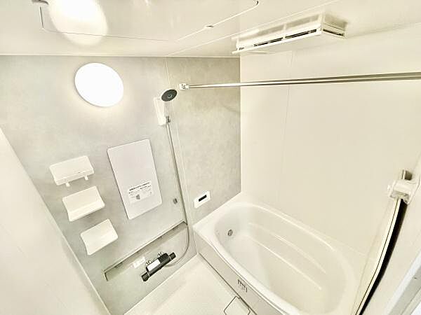 明るい照明が特徴的なバスルームです。シンプルで清潔感のある空間が広がっています。壁面には便利な棚や設備が充実しています。浴槽もしっかりとしたサイズ感があり使いやすさが感じられます。