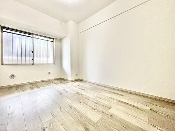 明るい色合いのフローリングが特徴的な洋室です。シンプルな内装でお好みのレイアウトが楽しめます。大きな窓からたっぷりと自然光が入ります。清潔感のある空間が印象的です。