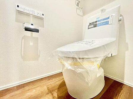 清潔感のあるトイレ空間です。壁リモコンがすっきりと設置されており使いやすさが感じられます。床は木目調でお手入れしやすい仕様です。設備が整っており使い勝手の良い印象です。