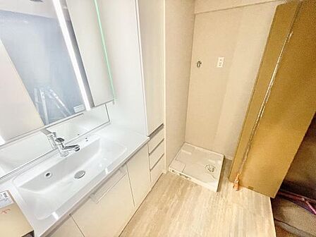 清潔感のある洗面台と広々とした洗面所が魅力です。収納スペースも豊富で日常の使い勝手に配慮されています。洗濯機の設置スペースもしっかり確保されています。シンプルなデザインが印象的です。