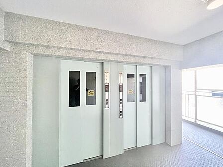 明るい共用部に設置されたエレベーターが日々の移動をスムーズにサポートします。ゆとりのある出入口で使いやすさが特長です。清潔感のある空間が印象的です。複数基設置されており混雑時も安心です。