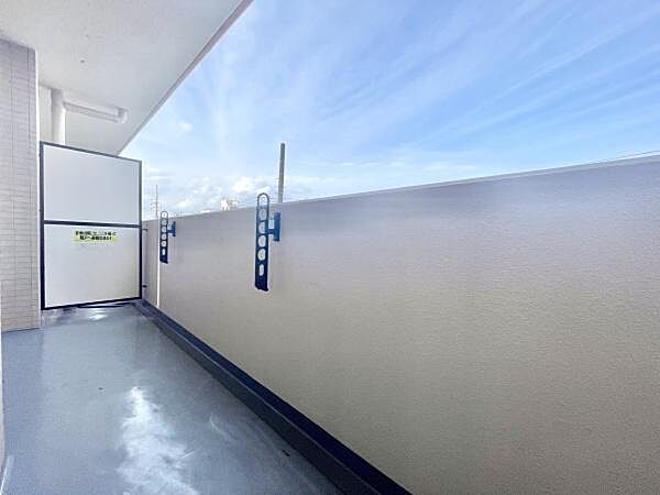 開放的な空間が広がるバルコニーです。明るい空と相性の良いシンプルなデザインが特徴です。使いやすい洗濯物干し金具も備え付けられています。