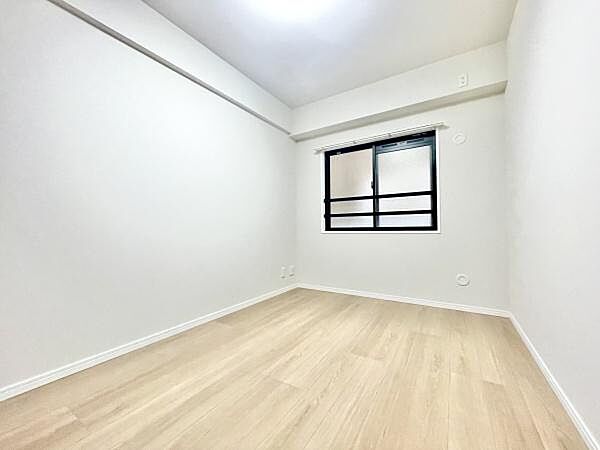 白を基調とした洋室でシンプルなデザインが印象的です。窓からの自然光が室内を明るく演出しています。フローリングの質感が清潔感を強調しています。さまざまなインテリアが合わせやすいお部屋です。