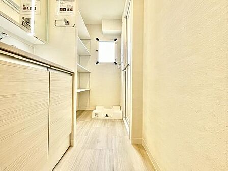 明るい色調の内装が印象的な洗面所です。収納スペースも充実しており整理整頓しやすい設計です。室内窓から自然光が差し込むため清潔感を感じられます。使いやすさを重視したレイアウトも特徴です。