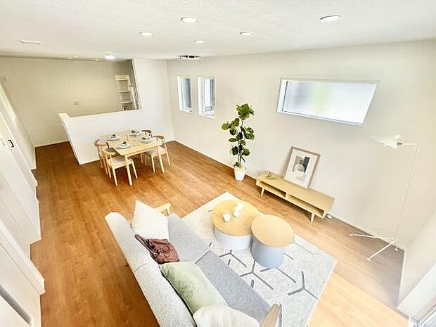 明るい窓から自然光が差し込みリビング全体が開放的な雰囲気です。落ち着いた色合いの床材と白を基調とした壁が空間を広く見せています。家具やインテリアもシンプルで統一感があります。