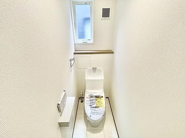 コンパクトで使いやすいトイレ空間です。窓が設置されており自然光が入る明るい印象です。白を基調とした内装が清潔感を演出しています。換気扇も備わっており空気の入れ替えが可能です。