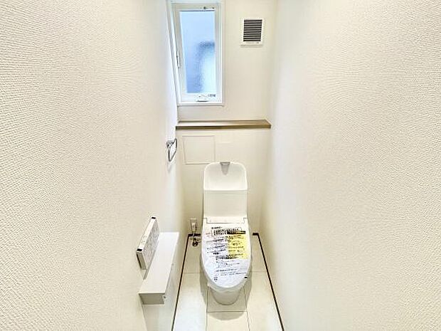 コンパクトで使いやすいトイレ空間です。窓が設置されており自然光が入る明るい印象です。白を基調とした内装が清潔感を演出しています。換気扇も備わっており空気の入れ替えが可能です。